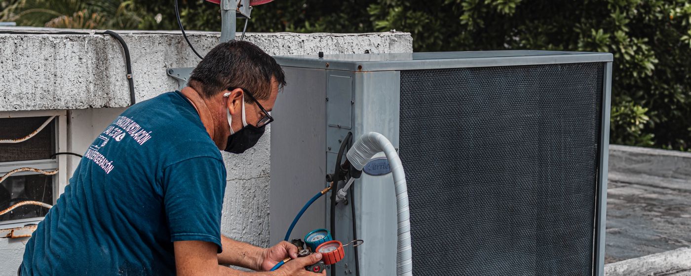 Un installateur RGE au travail sur le groupe extérieur d'une climatisation réversible